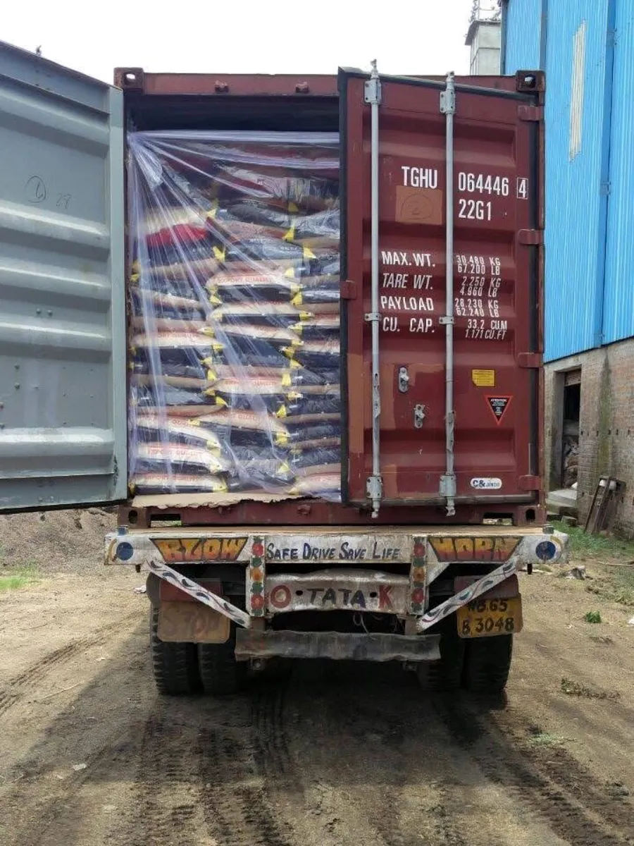 Stuffed 20ft container on a trailer, bags wrapped in a plastic liner, one door open